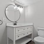 Modern white bathroom vanity with sink and round mirror, ideal for premium cabinet spaces.