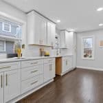 Bright modern kitchen with premium white cabinetry and gold hardware, showcasing expert cabinet design.