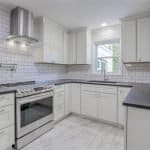 White modern kitchen with custom cabinets and granite countertops, perfect for home renovation.