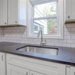 Elegant white kitchen cabinets with black granite countertop and subway tile backsplash, showcasing premium cabinetry.