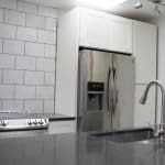 Modern white kitchen cabinets with stainless steel appliances and black countertops for premium cabinetry.