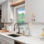 Sleek white kitchen cabinetry with copper handles and modern backsplash design.