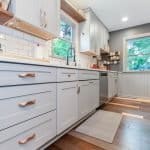 Sleek light gray kitchen cabinets with copper handles in modern kitchen interior.
