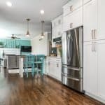 Bright modern kitchen with white cabinets, stainless steel appliances, and hardwood flooring.
