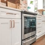 Shaker-style kitchen cabinets with copper handles in a modern white kitchen.