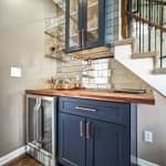 Sleek navy blue custom cabinets with wooden countertop for stylish home bar area.