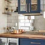 Sleek blue kitchen cabinets with glass doors, copper hardware, and modern glass shelving.