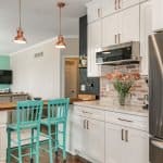 Sleek white kitchen cabinets with copper handles and brick backsplash, showcasing premium custom cabinetry.