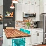 Colorful kitchen with custom white cabinets, brick backsplash, and turquoise barstools.
