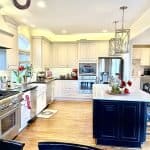 Elegant white kitchen cabinets with black countertops and a spacious central island, showcasing premium cabinet craftsmanship and kitchen design.