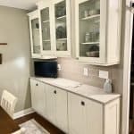 Sleek white kitchen cabinet with glass doors and granite countertop, designed by Premium Cabinet Studio.