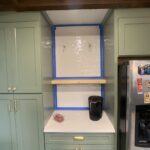 Bright green kitchen cabinetry with modern design, stainless steel appliances, and a white countertop.