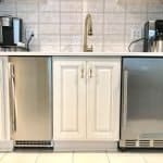 Polished white custom kitchen cabinets with stainless steel appliances and gold fixtures.