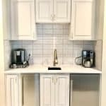 Elegant white kitchen cabinet design with modern appliances and decorative tile backsplash.