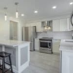 Modern white kitchen cabinets with stainless steel appliances and island.