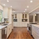 Elegant white kitchen cabinets with modern appliances and hardwood flooring in a stylish, bright kitchen.