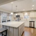 Bright white kitchen cabinets with modern stainless steel appliances and an spacious island.