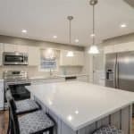 Modern white kitchen with premium custom cabinets and stainless steel appliances.