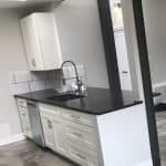Sleek white kitchen cabinets with black countertop and modern faucet setup, stylishly blending functionality and design.