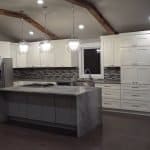Modern white kitchen cabinets with marble island and trendy backsplash.