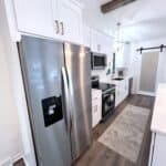 Stainless steel refrigerator with custom white kitchen cabinets, modern kitchen design, premium cabinet studio.