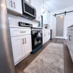 Sleek white kitchen cabinets with modern hardware and stainless steel appliances.