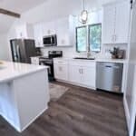 Modern white kitchen cabinets with stainless steel appliances and quartz countertops.