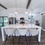 Sleek white kitchen cabinets with modern hardware in a contemporary kitchen with island and pendant lights.