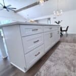 Bright white custom kitchen island with modern hardware in a spacious, contemporary home.