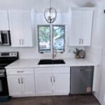 Elegant white kitchen cabinets with modern stainless steel appliances and black sink, showcasing premium cabinetry from Overland Park Cabinets.