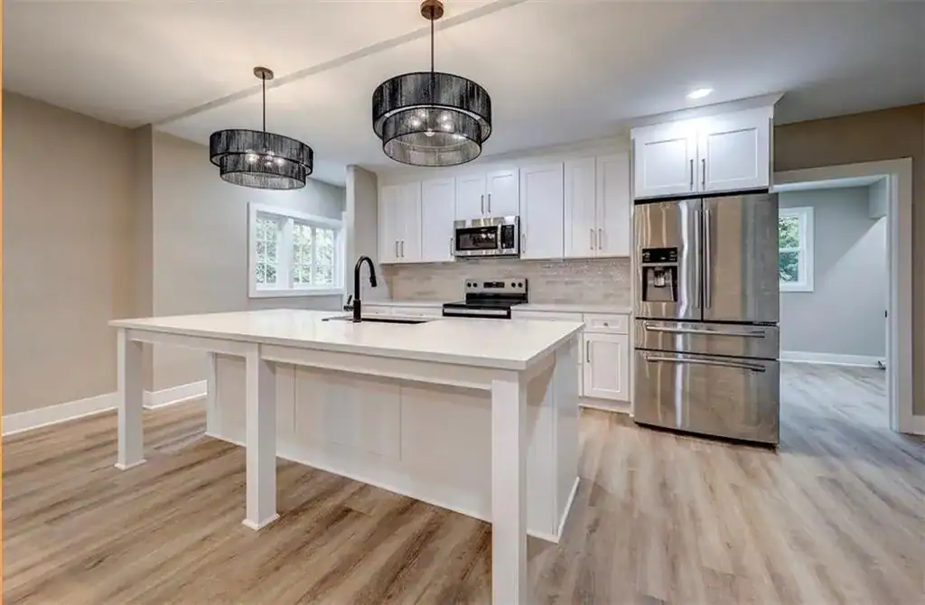 Finished white shaker kitchen with quartz island, French door refrigerator, and black pendant lights — Merriam, KS remodel