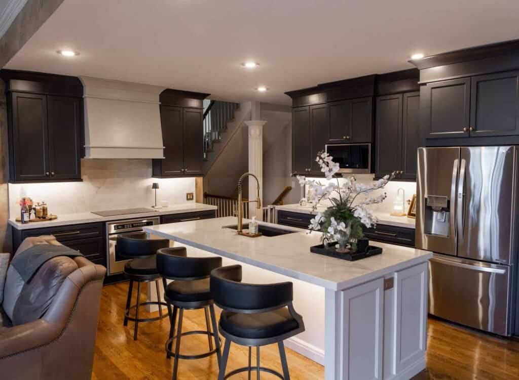 Charcoal gray shaker cabinets with a white quartz waterfall island, gold fixtures, and stainless steel appliances in a Shawnee, KS kitchen remodel by Premium Cabinet Studio.