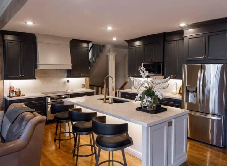 Charcoal gray shaker cabinets with a white quartz waterfall island, gold fixtures, and stainless steel appliances in a Shawnee, KS kitchen remodel by Premium Cabinet Studio.