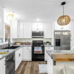 Renovated kitchen in Raytown, MO with white shaker cabinets, granite countertops, stainless steel appliances, and wood accent island