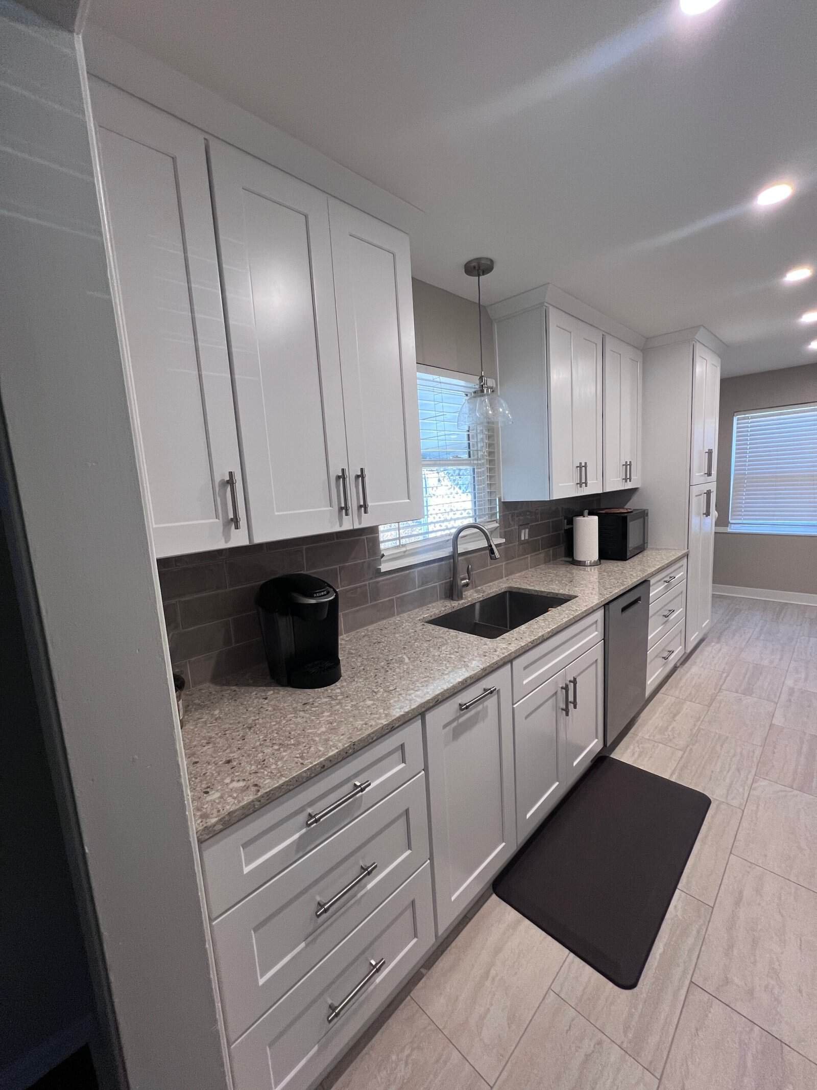 Modern white kitchen cabinets with granite countertops and stainless steel hardware.