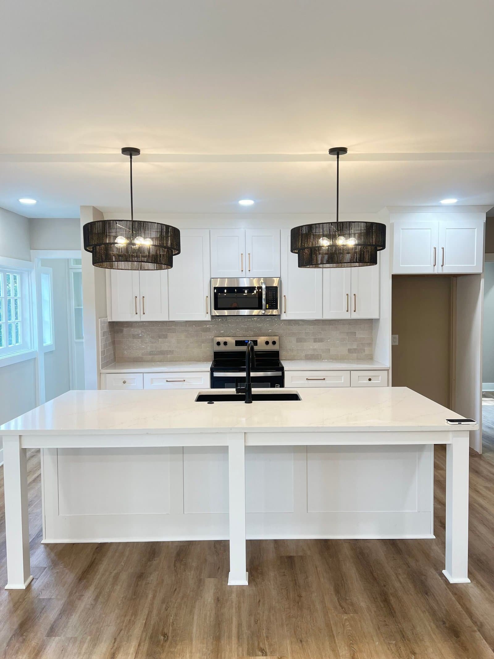 White shaker cabinet kitchen with quartz island, black pendant lights, and tile backsplash — custom remodel in Merriam, KS