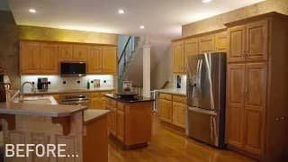 Before kitchen remodel in Shawnee, KS with golden oak cabinets, black countertops, and stainless steel appliances