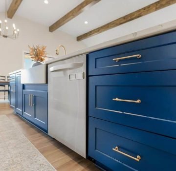 Blue shaker kitchen island with a farmhouse sink and stainless steel appliances in De Soto, KS