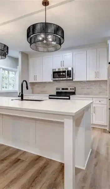 Finished white shaker kitchen with quartz island, French door refrigerator, and black pendant lights — Merriam, KS remodel
